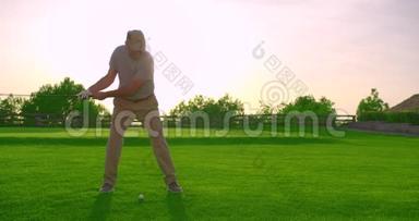 年轻英俊的高尔夫球手，日落时在美丽的球场上<strong>挥杆</strong>击球。